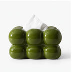 Glossy olive green tissue box cover with a bubble-like design, holding a white tissue, against a plain white background.