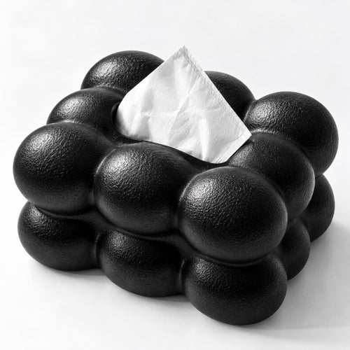 Black textured holder made of spherical bumps with a white tissue peeking out from the top opening.