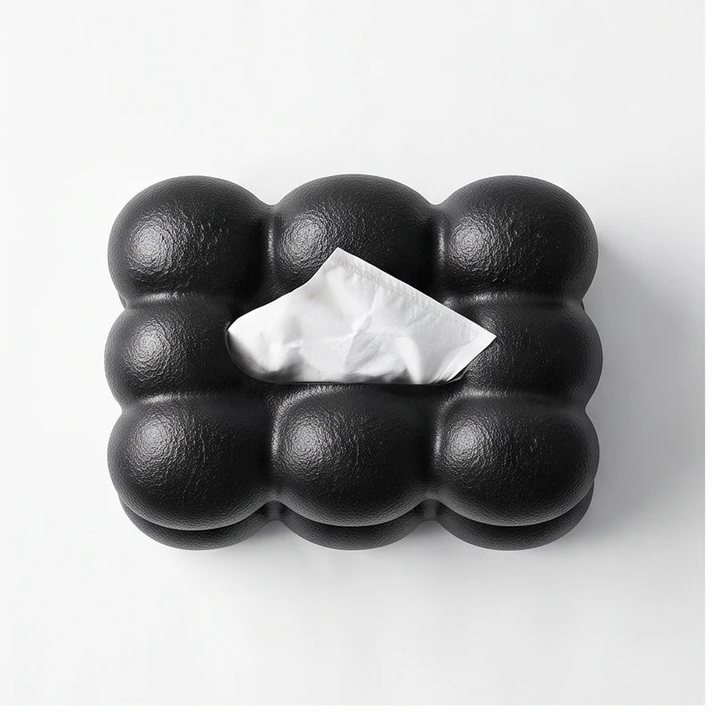 Black bubble-textured tissue box with a single white tissue peeking from the top opening, against a white background.