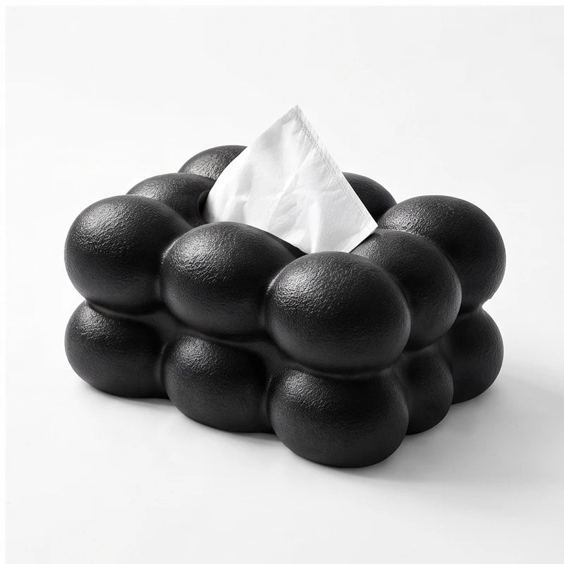 Black bubble-textured tissue box with a single white tissue protruding from the top, against a white background.