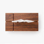 Flat lay of a rectangular dark wood tissue box with visible grain and a white tissue emerging from the top slot.
