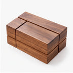 Geometric wooden object with dark brown grain, made of multiple rectangular blocks forming a hollow center on a white background.