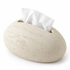 Light beige, pebble-shaped tissue holder with a rough, textured finish and a white tissue emerging from the top slot.