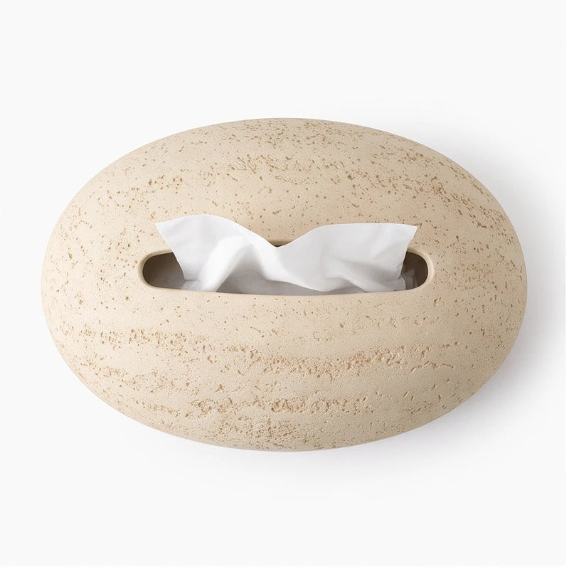 Light beige, pebble-shaped textured dispenser with an oblong opening from which white tissues emerge, isolated on white.