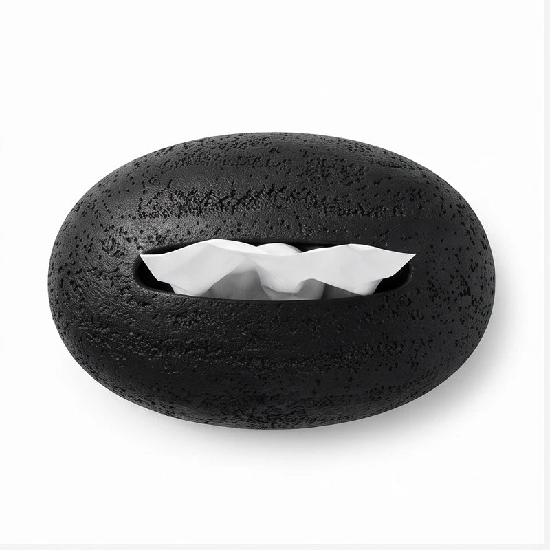 Black oval tissue box with a rough, textured surface and white tissues pulled partly from its central opening.